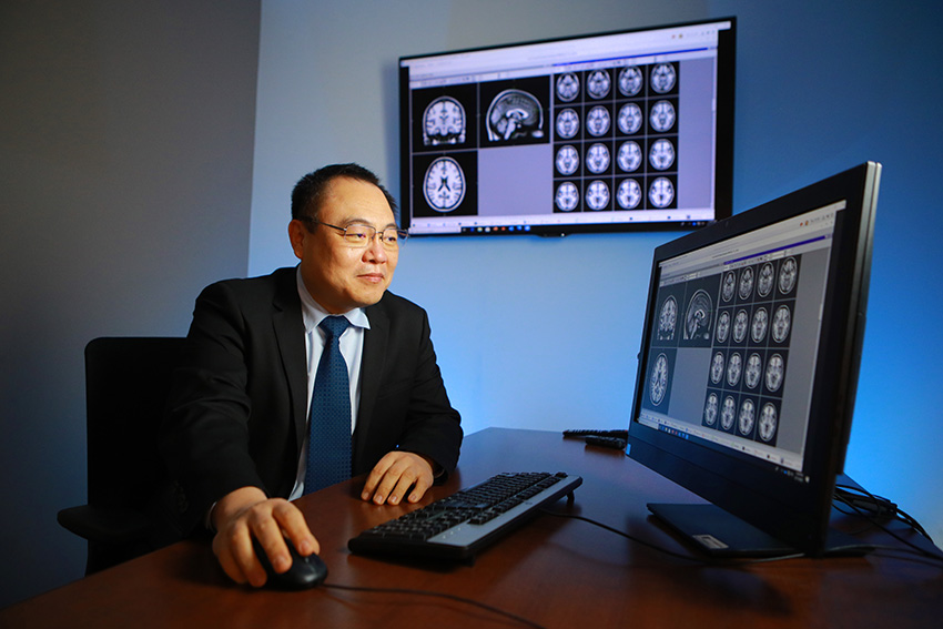 Xin Wang, M.D., Ph.D., looking at MRI images on a computer